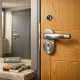Pasillo espau00f1ol con dos puertas de entrada, una de roble y otra gris, mostrando cerraduras seguras y diseu00f1o; Que tipos de puertas de entrada ofrecen mejor combinacion de seguridad y estetica